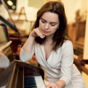Eine Klavierlehrerin sitzt grübelnd und besorgt am Klavier